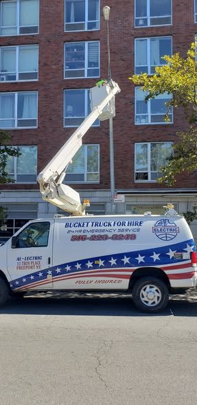 Bucket raised against a red brick apartment building, with our wrapped van parked below