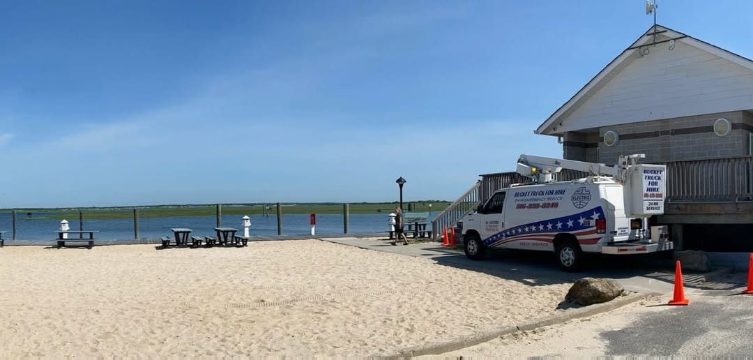 Our van parked on the sand beside a beach pavilion, with safety cones set out