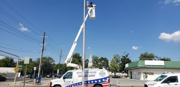 Bucket raised to a tall light pole at an intersection next to a shopping center
