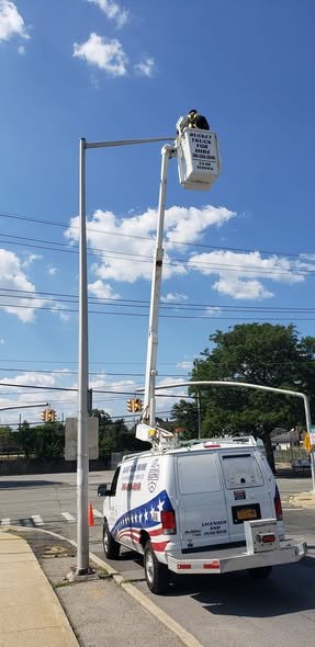 Bucket raised to the top of a street light pole at a street corner
