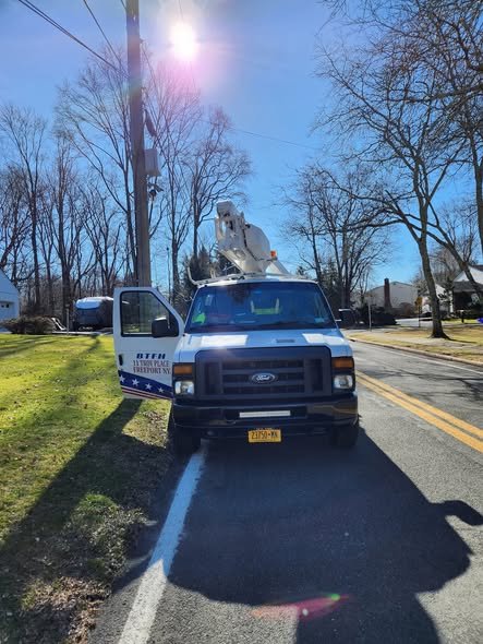 Front view of our bucket van parked on a road shoulder next to a utility pole